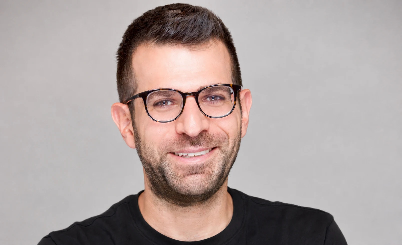 Portrait of Ori Mor wearing glasses against a light gray background